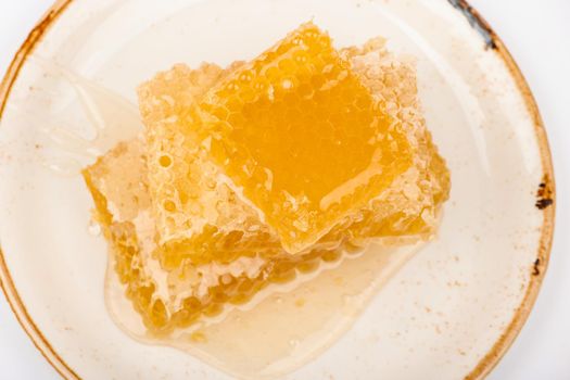 Close up stack of several fresh cut golden comb honey slices on plate isolated on white background, elevated top view, directly above