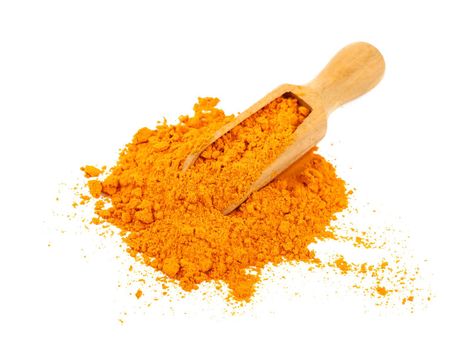 Close up one wooden scoop full of yellow turmeric spice powder spilled and spread around isolated on white background, high angle view