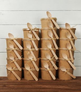 Close up stack of many brown paper cups with dessert at coffee shop retail display with copy space of white wall, low angle view