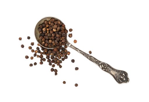 Close up one vintage metal spoon full of black pepper peppercorns and heap of peppercorns spilled and spread around isolated on white background, elevated top view, directly above