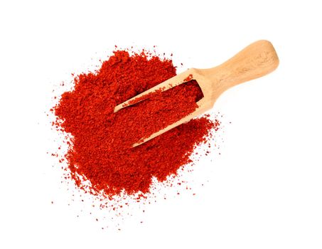 Close up one wooden scoop full of red chili pepper, paprika or sundried tomato powder spilled and spread around isolated on white background, elevated top view, directly above