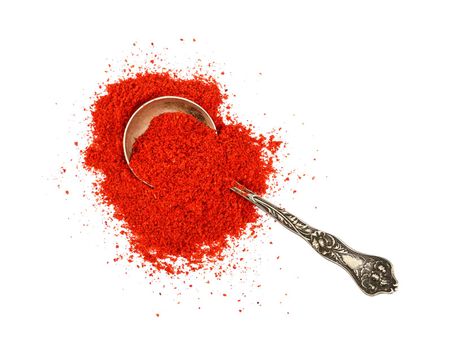 Close up one vintage metal spoon full of red chili pepper, paprika or sundried tomato powder spilled and spread around isolated on white background, elevated top view, directly above