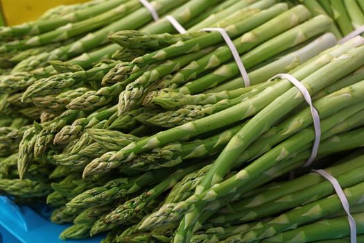 Bunch of fresh green asparagus shoots at retail market display, close up, high angle view