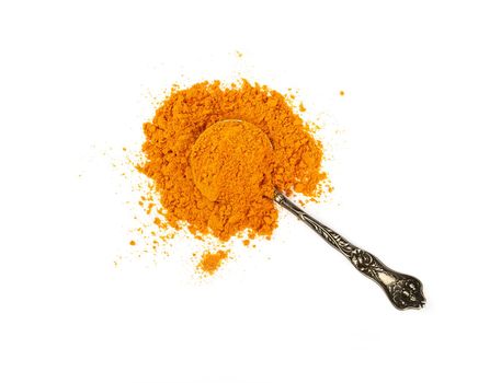 Close up one vintage metal spoon full of yellow turmeric spice powder spilled and spread around isolated on white background, elevated top view, directly above