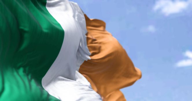 Detail of the national flag of Ireland waving in the wind on a clear day. Democracy and politics. Northern Europe country. Patriotism. Selective focus.