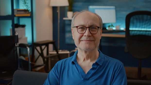 Portrait of senior man with injury smiling and looking at camera next to transportation equipment for accessibility and physical support. Old person dealing with disability in living room.