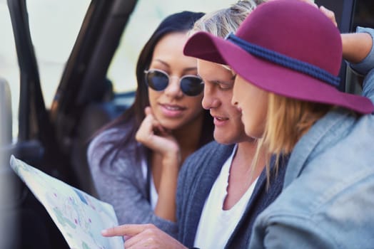Portrait of a group of friends leaning against their van, reading a map