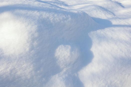Snow texture. The wind drew patterns on the snowy surface. The wind sculpts patterns and ridges on the surface of the snow. Various shades of white on the surface of snowdrifts.