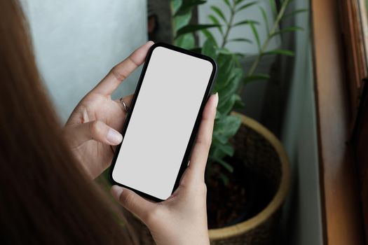 cell phone blank white screen mockup.woman hand holding texting using mobile on desk at office.background empty space for advertise.