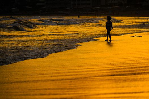 Kid playing at dusk waves. Shooting Location: Kamakura City, Kanagawa Prefecture