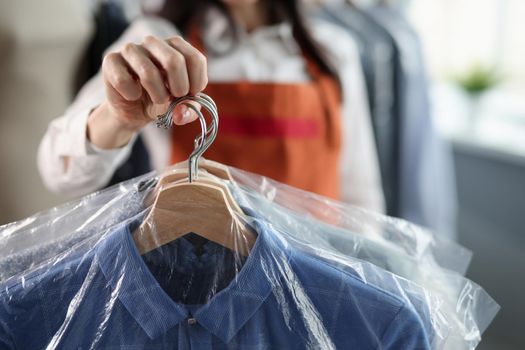 Professional worker keeps clean clothes on hangers. Laundry and dry cleaning services concept