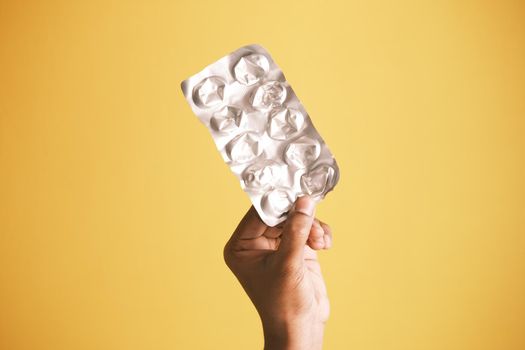 holding empty pills of blister pack against yellow background ,