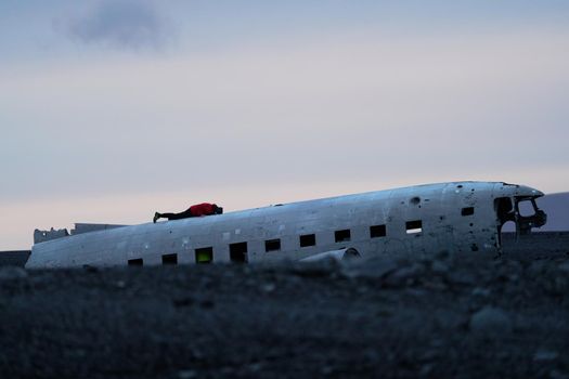 Wreck of and airplane profile and tourist laid down at dusk