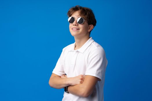 Teen boy in glasses and shirt isolated on blue background, close up