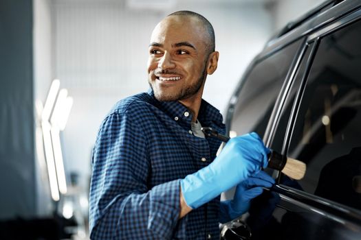 African American man car service worker applying nano coating on a car, close up