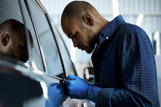 African American man car service worker applying nano coating on a car, close up