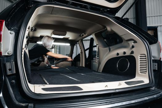 Worker woman vacuum cleaning dust interior inside car in car wash, close up