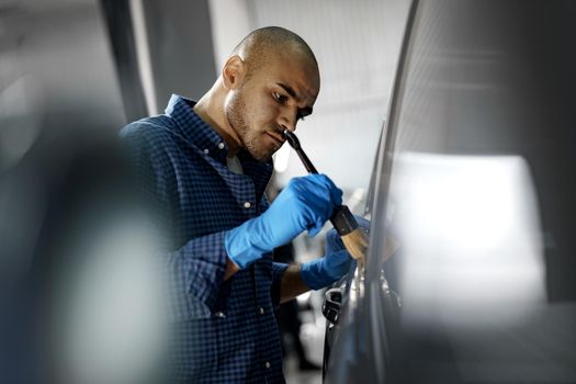 African American man car service worker applying nano coating on a car, close up