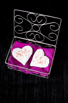 Cookies in the form of heart lies in a casket with pink cloth.