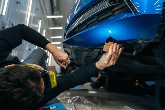 Car detailing. Man applies nano protective coating to the car in car detailing service, close up