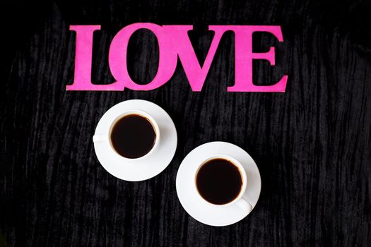 two cups of coffee on pink background inscription love Valentine's Day.