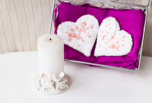 candle and biscuits in the form of heart on a pink napkin.