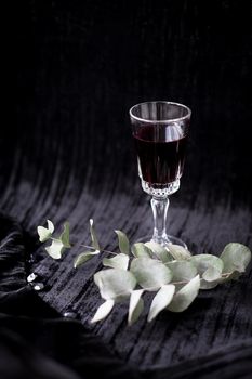 twig and glass of red wine on a black background Velvet.