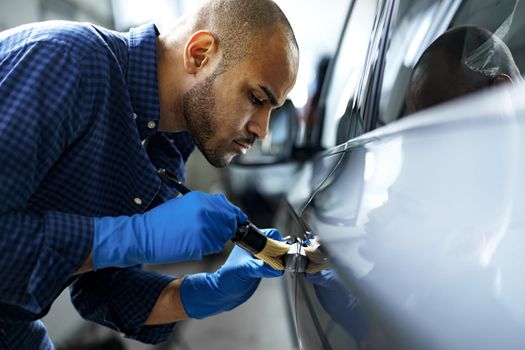 African American man car service worker applying nano coating on a car, close up