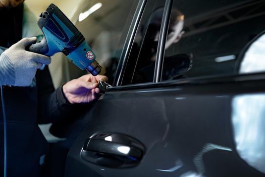Close up photo of male car service worker applying nano coating on a car