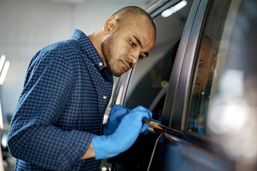 African American man car service worker applying nano coating on a car, close up