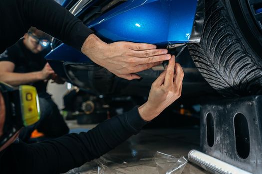 Car detailing. Man applies nano protective coating to the car in car detailing service, close up