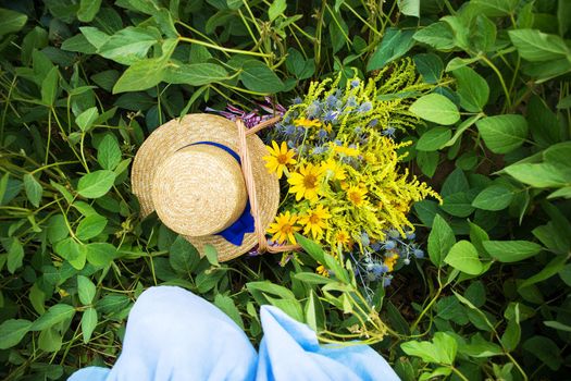 straw hat and basket with flowers stand on the grass, close-up.