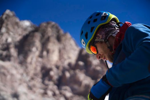 A man in special mountaineering glasses with a mirror-effect orange color, takes care of his eyesight and safety in the snowy mountains. The hiker travels in the mountains, is engaged in climbing.