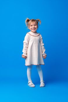 Full length portrait of a little girl standing on blue backgorund, close up