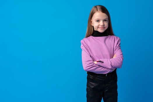 Portrait of a little smiling girl preteen on blue background, close up