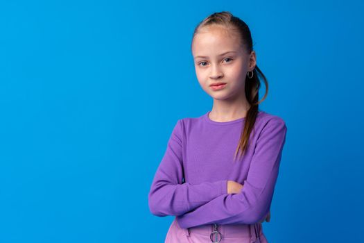 Portrait of a little smiling girl preteen on blue background, close up