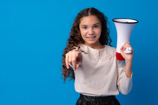 Cute schoolgirl holding megaphone against blue background, close up