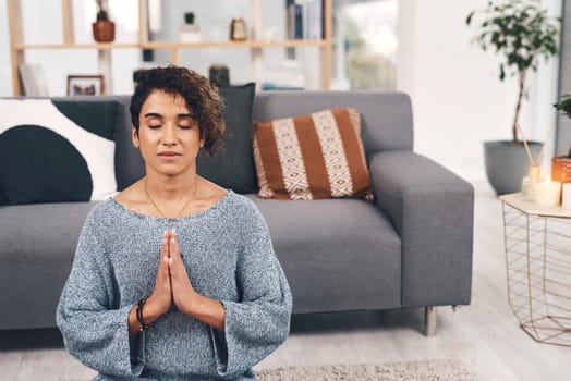 Cropped shot of an attractive young woman sitting and meditating in her living room at home