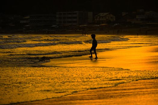 Kid playing at dusk waves. Shooting Location: Kamakura City, Kanagawa Prefecture