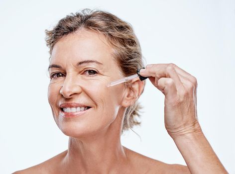 Shot of a mature woman posing with a serum dropper against her face