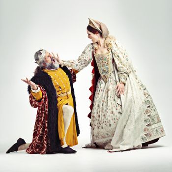 Studio shot of a queen slapping a kneeling king in the face