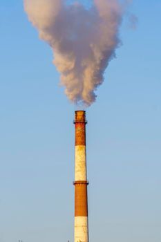 White thick smoke from the boiler room chimney. Smoke against the blue sky. Air pollution. Heating of the city. Industrial zone.