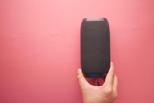 man's hand using smart speaker on red background .