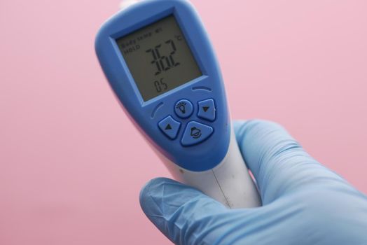 Hand holding infrared thermometer to measuring temperature