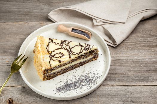 A Portion of the Poppy Seed Cake with Poppy Seeds served on the white plate on the rustic wooden table