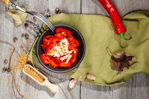 Chopped and pickled Red Hot Chili Pepper Canning Appetizer with garlic and mustard served in a black bowl on the wooden rustic style table