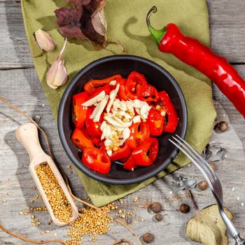 Chopped and pickled Red Hot Chili Pepper Canning Appetizer with garlic and mustard served in a black bowl on the wooden rustic style table