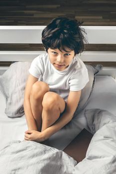 Little boy suffering from sleep disorder sitting in his bed 