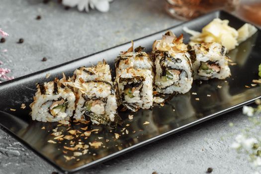 Golden dragon sushi roll with tuna, eel, cucumber, sesame seeds and tobiko caviar on wood background.