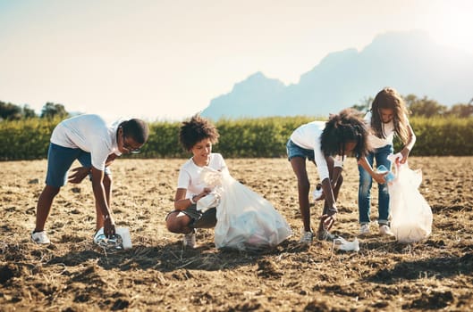 Shot of a group of teenagers picking up litter off a field at summer camp